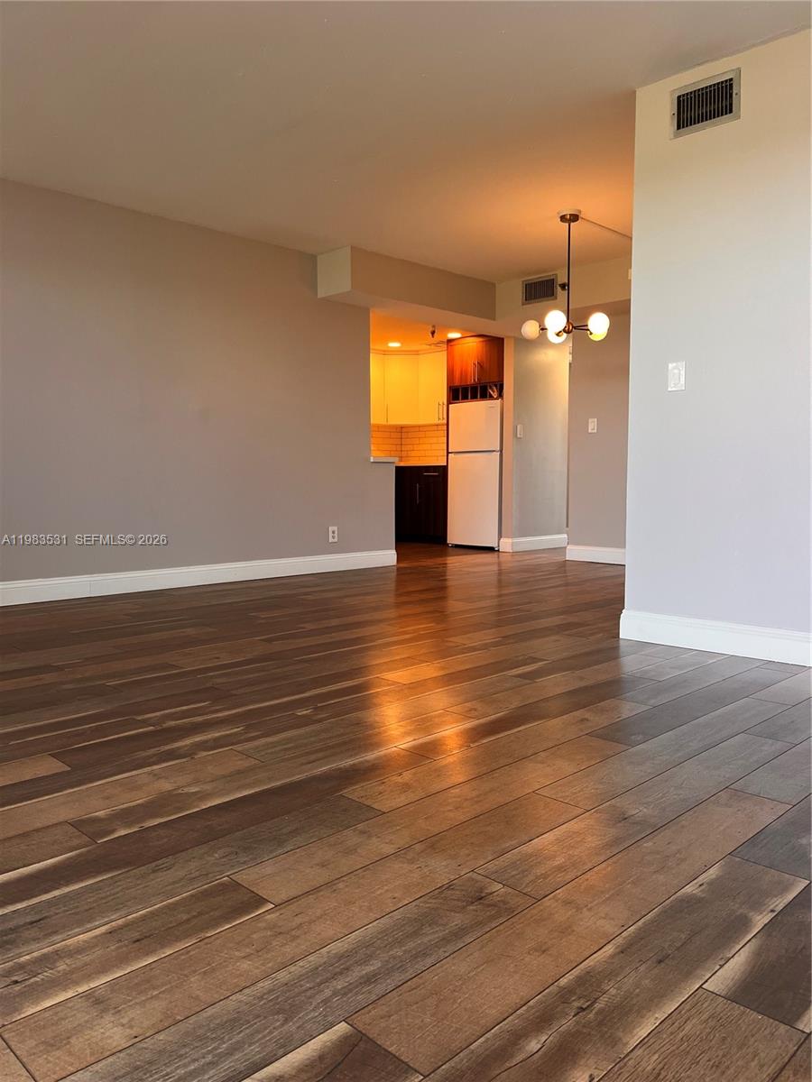 A view of a living area with wood-look flooring leading to an open kitchen — 3100 W Rolling Hills Cir # 403, Davie FL 33328, DAVIE, FL