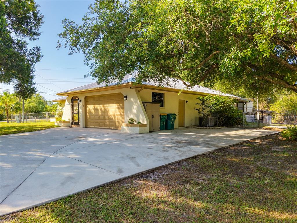 A tan house with a metal roof, a two-car garage, and a large concrete driveway — 27505 SENATOR DRIVE, PUNTA GORDA, FL
