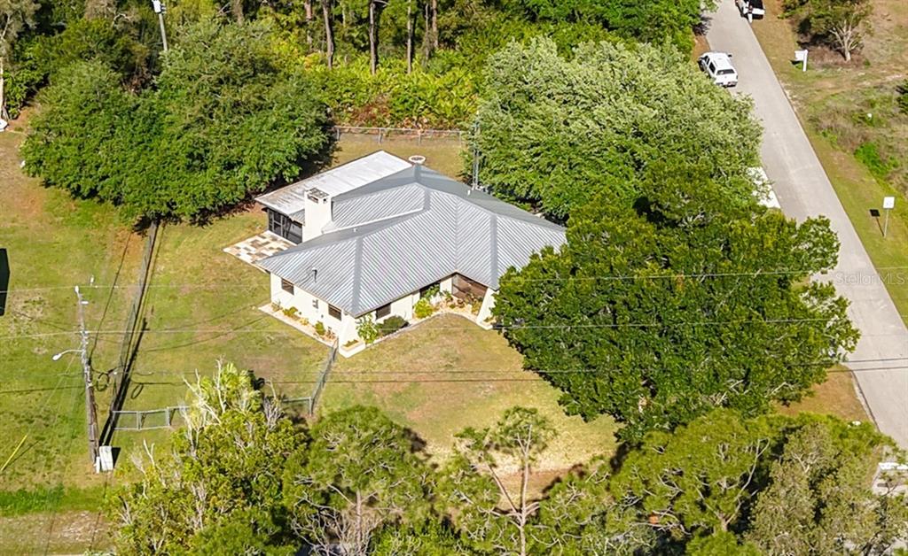An aerial view shows a house with a metal roof surrounded by trees and grass — 27505 SENATOR DRIVE, PUNTA GORDA, FL