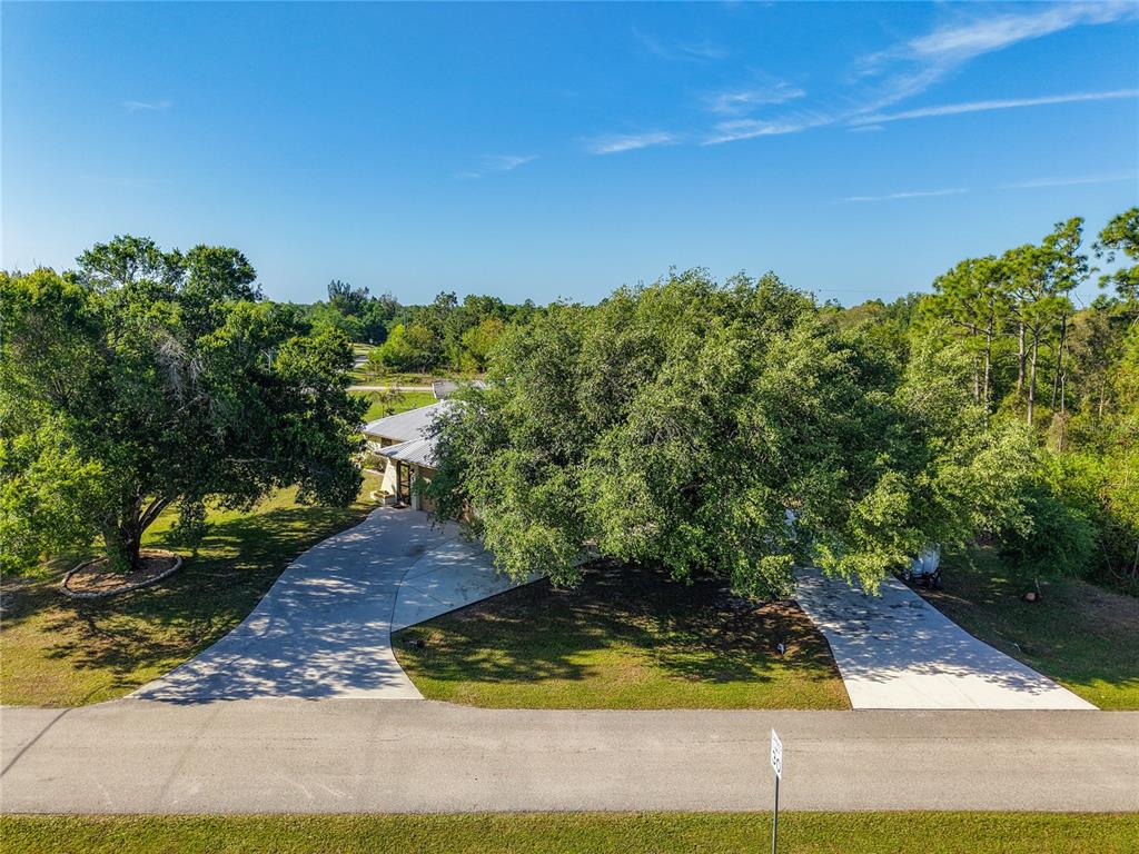An aerial view shows a house partially obscured by large trees with two concrete driveways — 27505 SENATOR DRIVE, PUNTA GORDA, FL