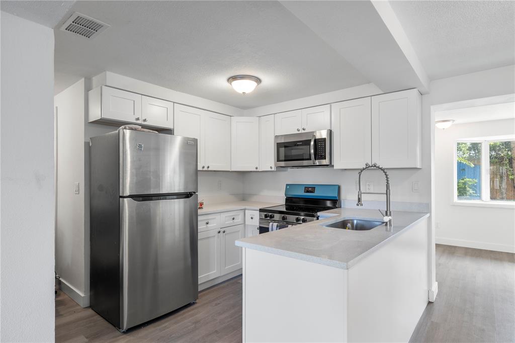 A kitchen with white cabinets, stainless steel appliances, and a gray countertop peninsula — 4711 BEACON HILL DRIVE, NEW PORT RICHEY, FL