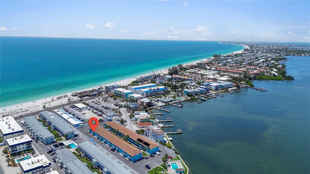 An aerial view shows a multi-story apartment complex with a red location pin — 117 7TH STREET N UNIT 2, BRADENTON BEACH, FL