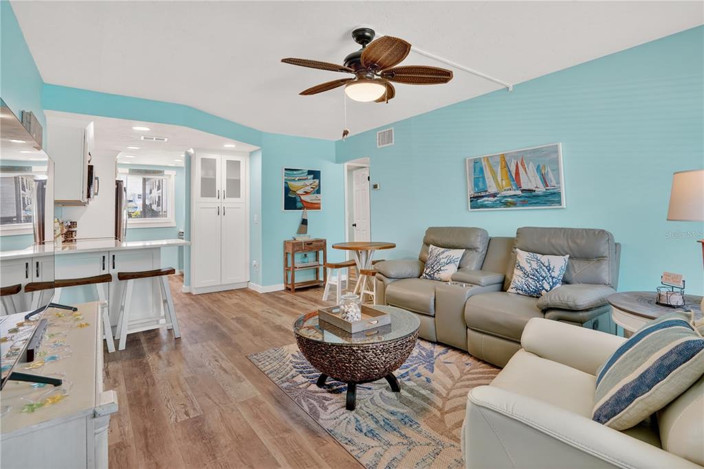 A living room with light blue walls, wood-look flooring, a ceiling fan, and gray furniture — 117 7TH STREET N UNIT 2, BRADENTON BEACH, FL