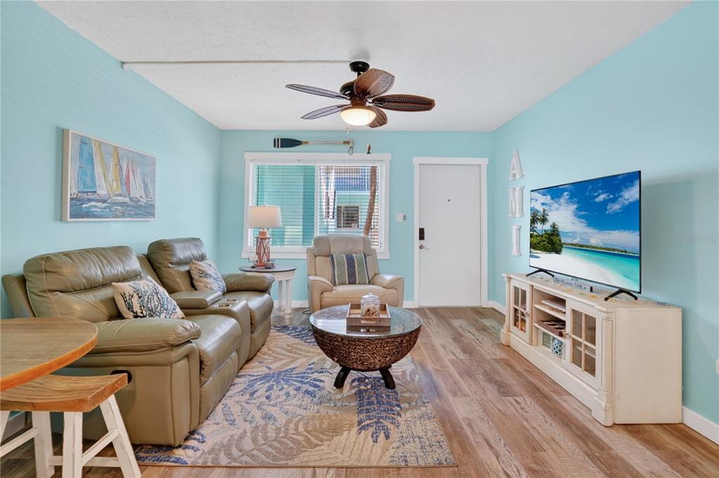 A living room features light blue walls, a ceiling fan, a sofa, and a television — 117 7TH STREET N UNIT 2, BRADENTON BEACH, FL