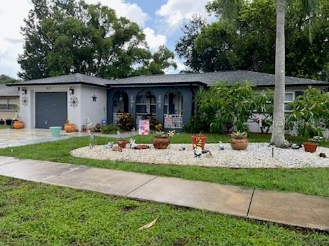 A single-story house with a gray exterior, arched entryway, and a white rock front yard — 3419 PALOMA DRIVE, HOLIDAY, FL