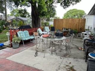 A concrete patio features a metal dining set, a small loveseat, and a wooden fence — 3419 PALOMA DRIVE, HOLIDAY, FL