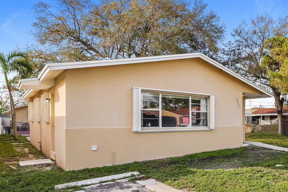 A single-story tan house with a large front window and a white roof overhang — HOLLYWOOD, FL