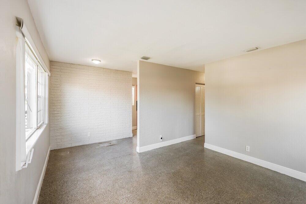 A room with light gray walls, a white brick accent wall, and polished concrete floors — HOLLYWOOD, FL