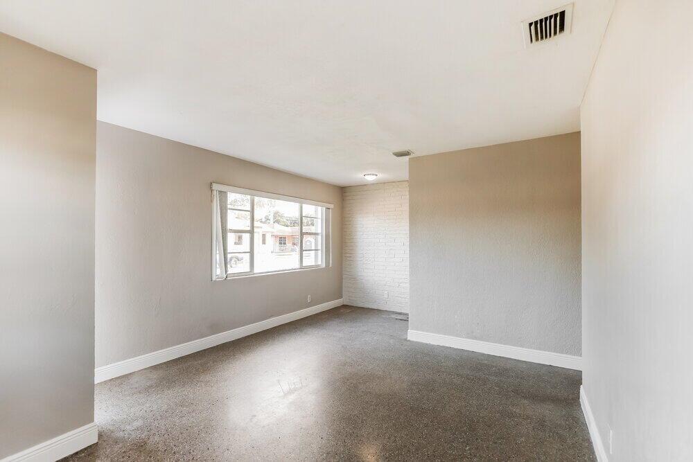 An empty room features gray walls, a white brick accent wall, and polished concrete floors — HOLLYWOOD, FL