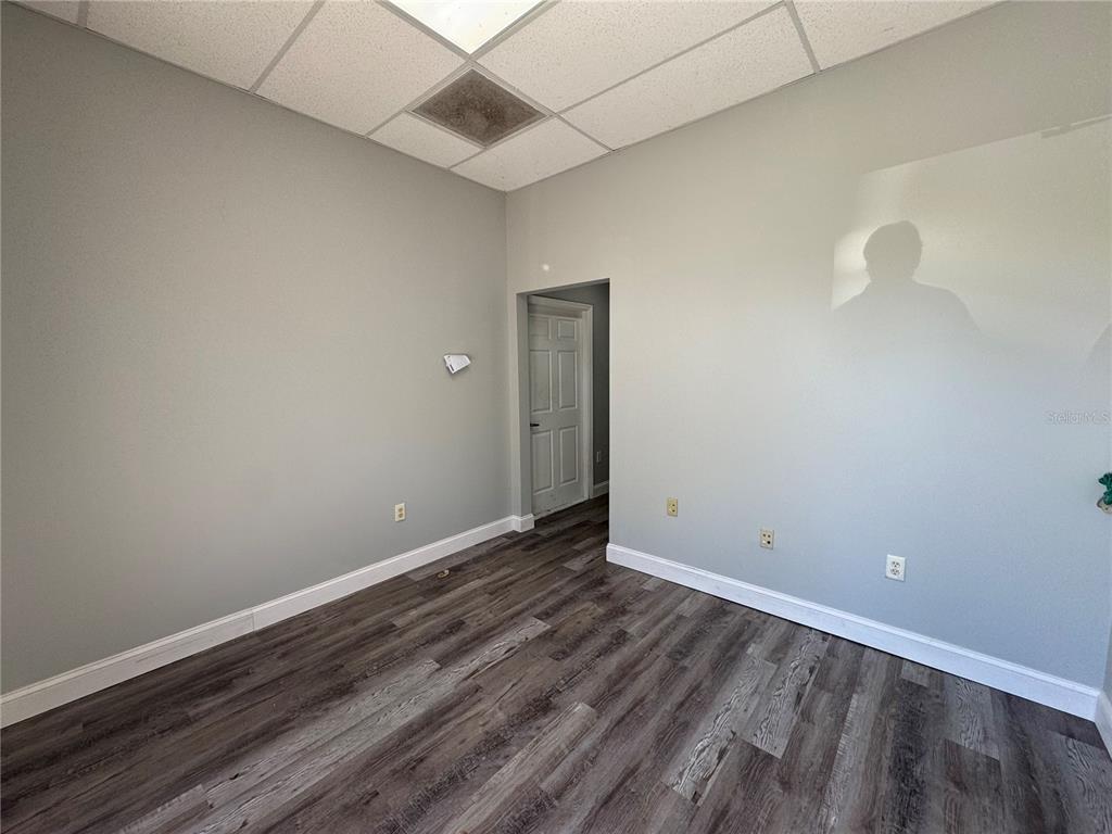 An empty room with gray walls, wood-look flooring, and a drop ceiling — 1408 HAMLIN AVENUE, ST CLOUD, FL