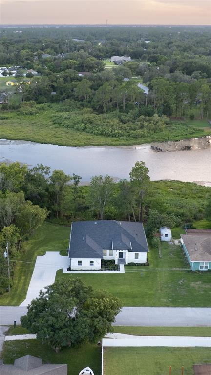 An aerial view shows a single-story house with a dark roof near a body of water — 1989 MONTEREY DRIVE, DELTONA, FL