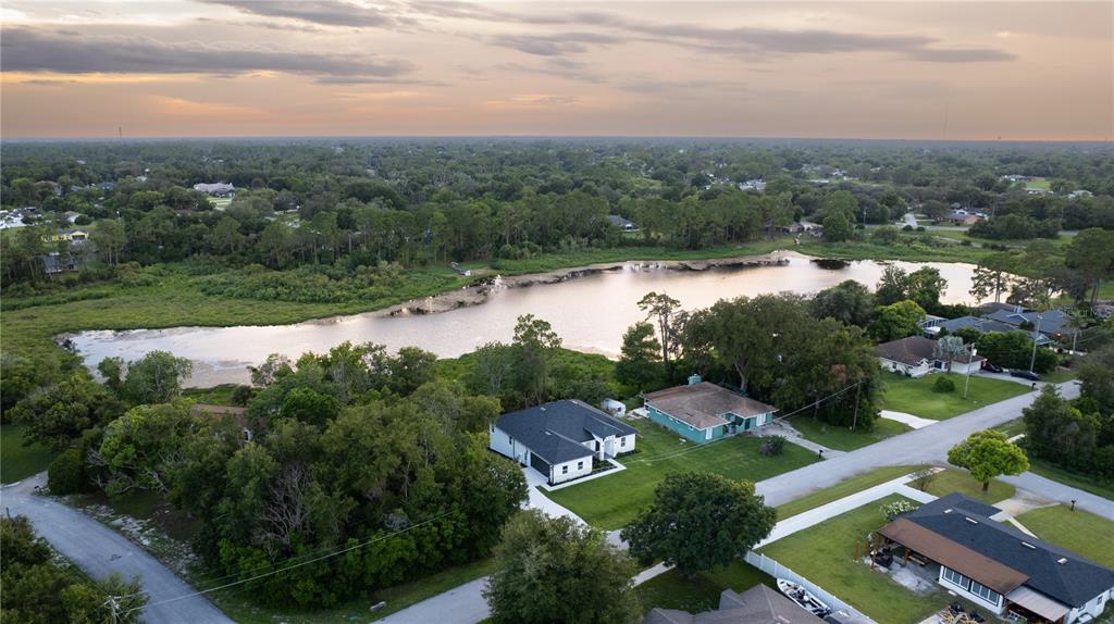 An aerial view shows a residential neighborhood with houses situated near a large lake — 1989 MONTEREY DRIVE, DELTONA, FL