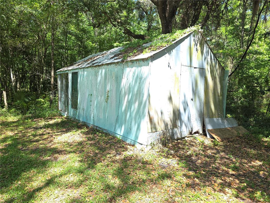 A weathered, light blue corrugated metal shed sits in a wooded area — 13499 OLD CRYSTAL RIVER ROAD, BROOKSVILLE, FL