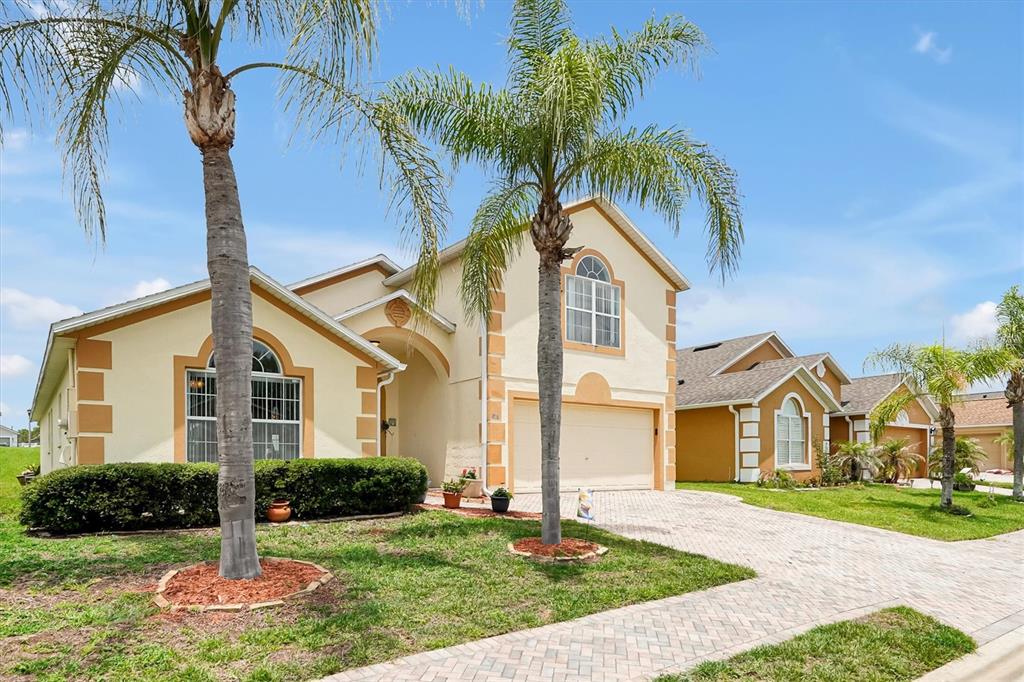 A two-story suburban house with a paved driveway, palm trees, and a tan stucco exterior — 816 KNIGHTSBRIDGE CIRCLE, DAVENPORT, FL