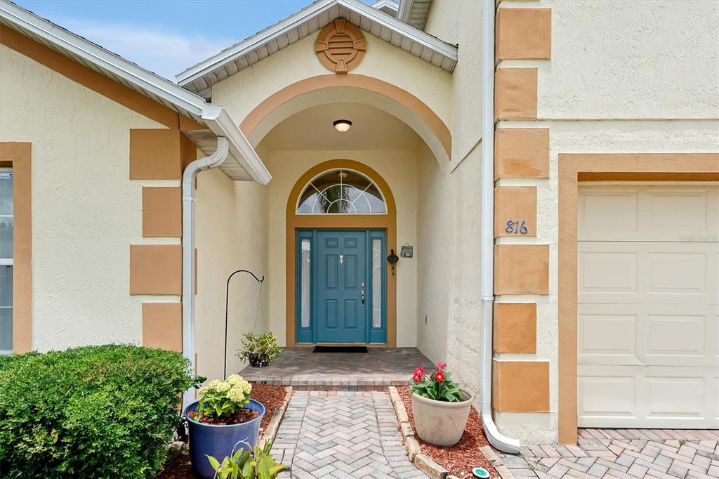 The exterior of a house features a blue front door, arched entryway, and brick walkway — 816 KNIGHTSBRIDGE CIRCLE, DAVENPORT, FL