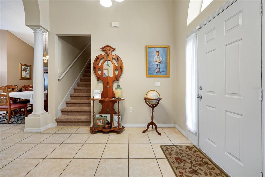 An entryway features tile flooring, a staircase, a wooden hall tree, and a globe stand — 816 KNIGHTSBRIDGE CIRCLE, DAVENPORT, FL