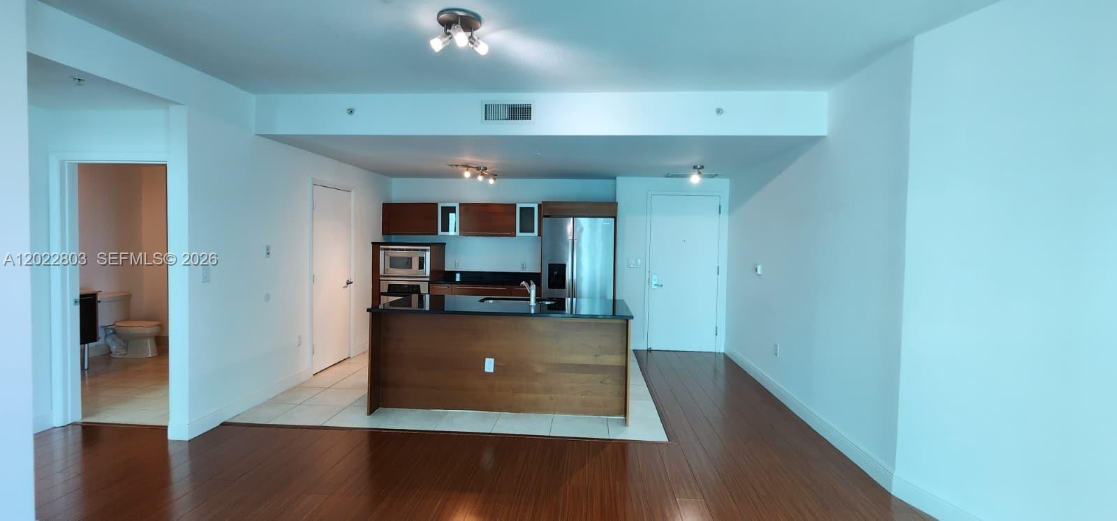 An open-concept kitchen features dark wood cabinetry, a central island, and hardwood flooring — 1900 N Bayshore Dr # 3717, Miami FL 33132, MIAMI, FL