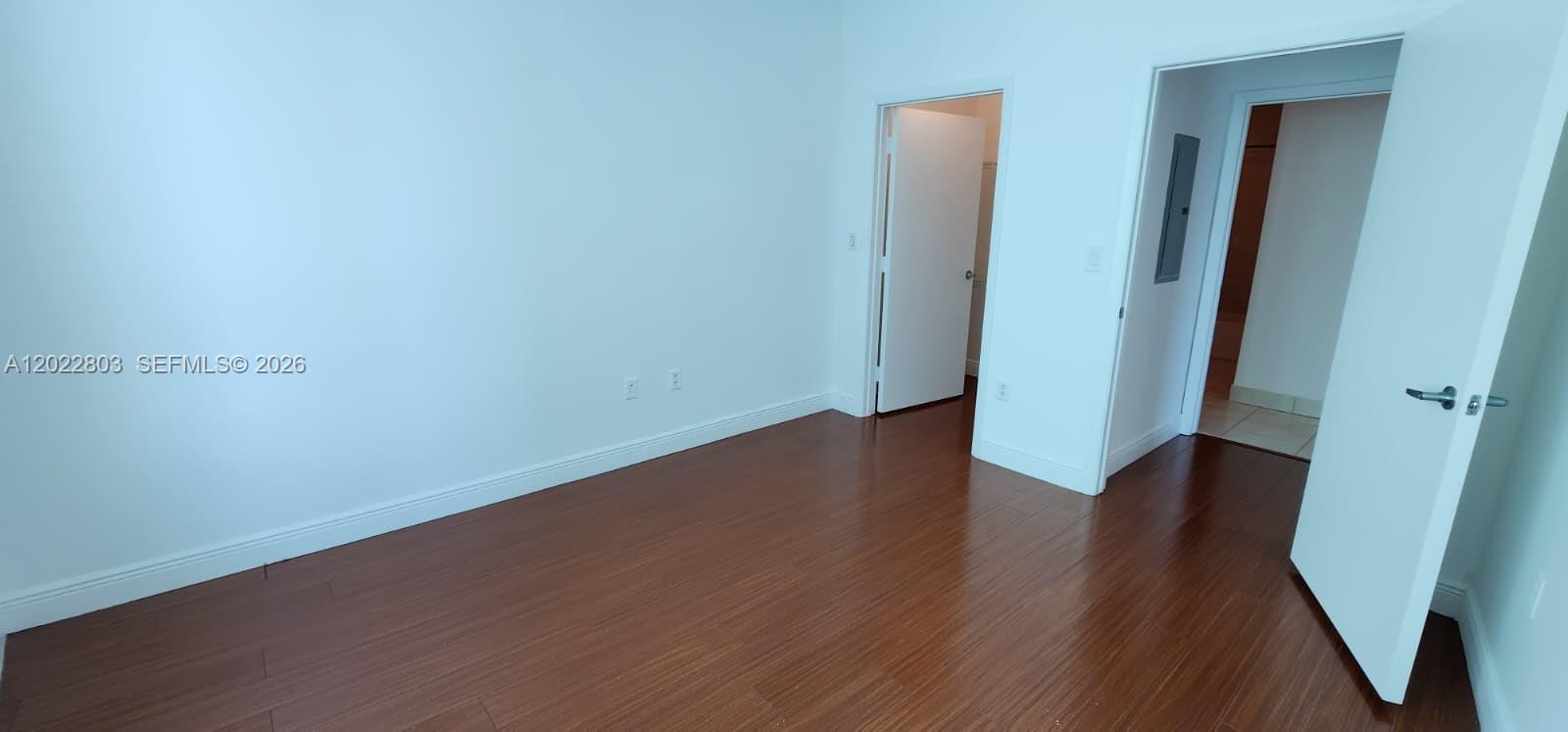 An empty room features dark wood flooring, white walls, and two open doorways — 1900 N Bayshore Dr # 3717, Miami FL 33132, MIAMI, FL