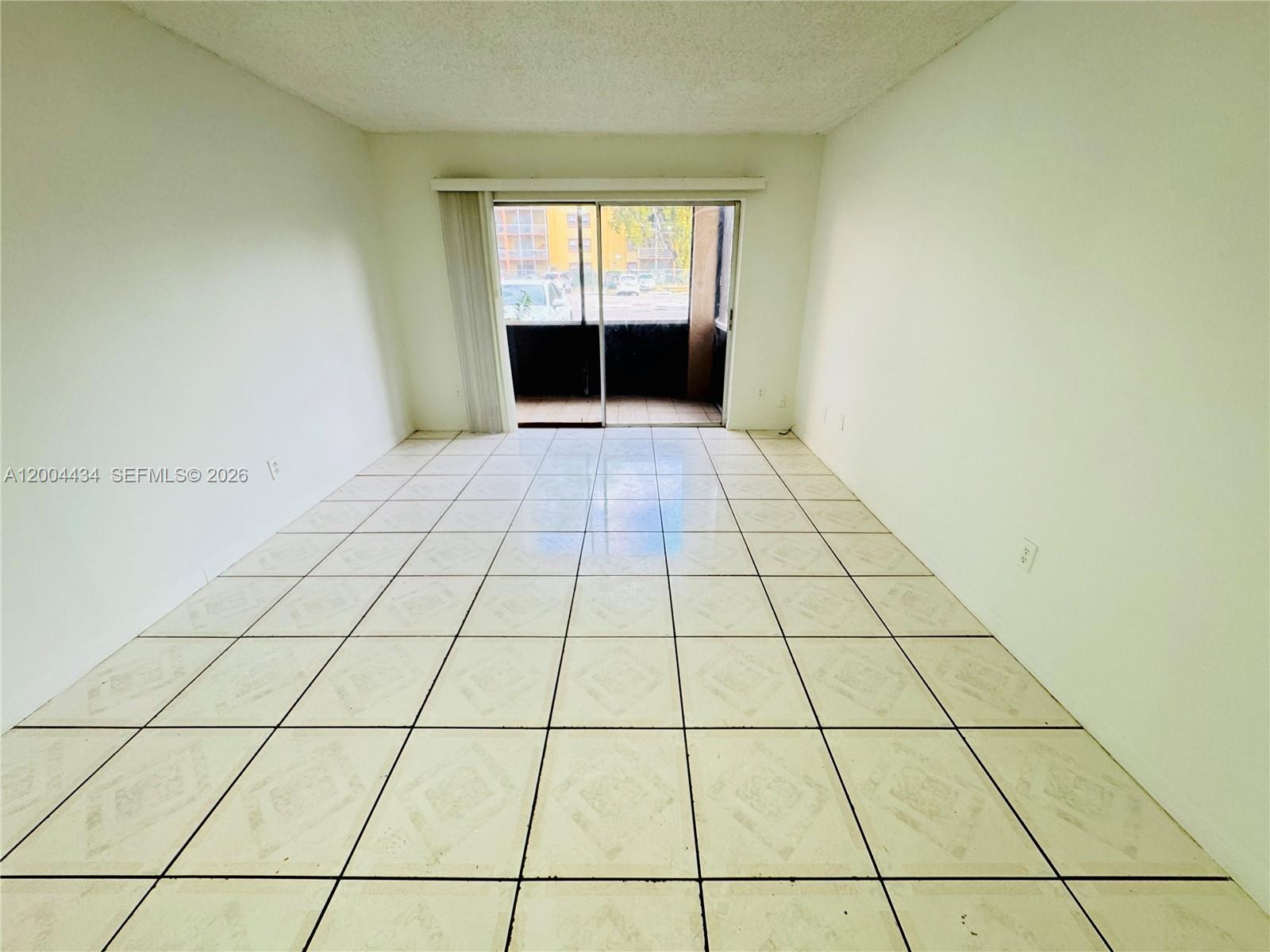 An empty room features white walls, light-colored tile flooring, and a sliding glass door — 2800 NW 56th Ave # D102, Lauderhill FL 33313, LAUDERHILL, FL