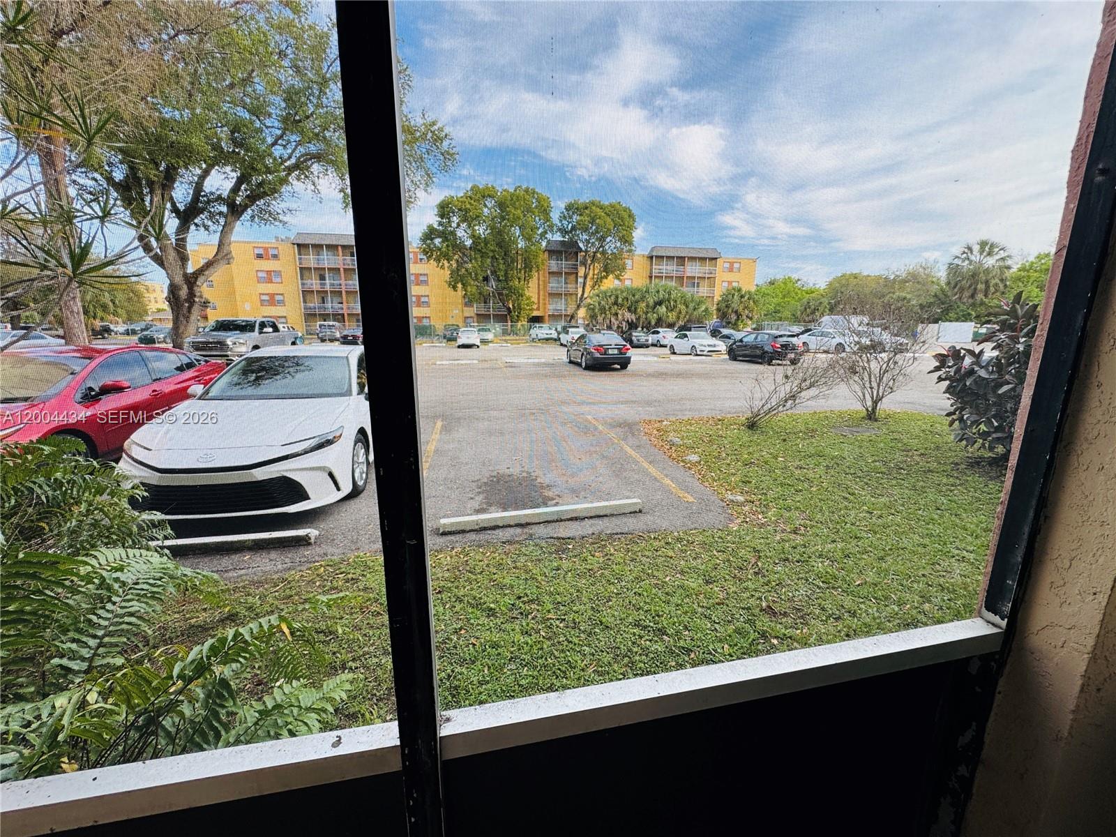 A view of a parking lot and apartment building seen through a screened-in porch — 2800 NW 56th Ave # D102, Lauderhill FL 33313, LAUDERHILL, FL
