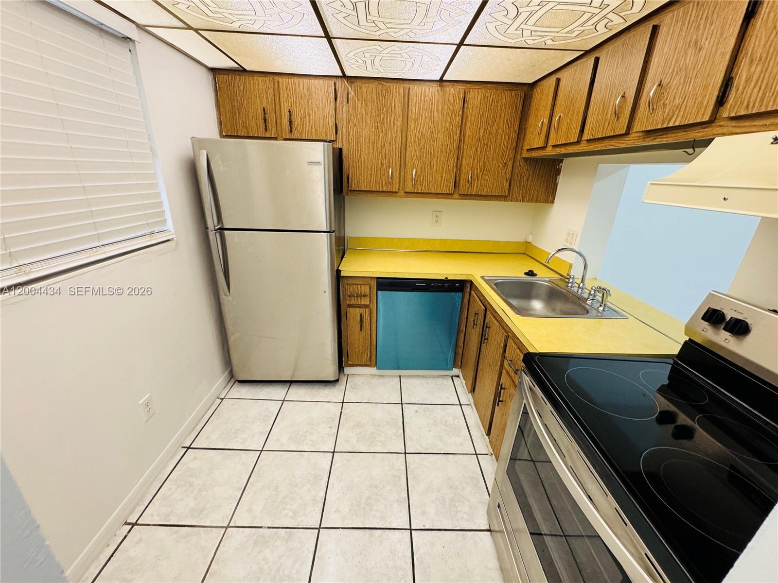 A kitchen features wood cabinets, yellow countertops, stainless steel appliances, and a tiled floor — 2800 NW 56th Ave # D102, Lauderhill FL 33313, LAUDERHILL, FL