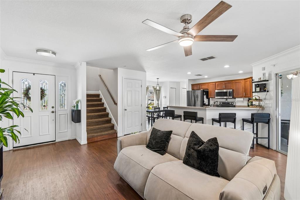 A living room with a beige sofa, wood flooring, and an open kitchen with bar seating — 222 CARPENTERS WAY UNIT 65, LAKELAND, FL