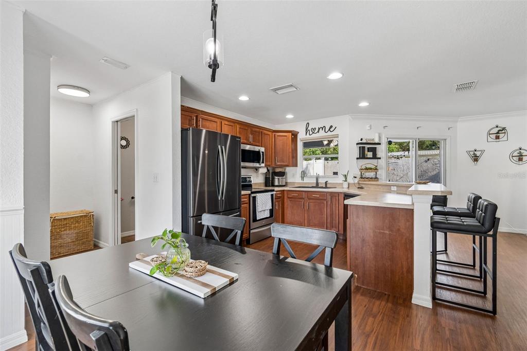 A kitchen with wood cabinets, stainless steel appliances, and a dining table in the foreground — 222 CARPENTERS WAY UNIT 65, LAKELAND, FL