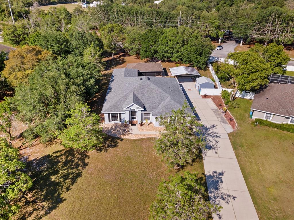 An aerial view of a single-story house with a gray roof, driveway, and detached shed — 900 BLANEY COURT, DELTONA, FL
