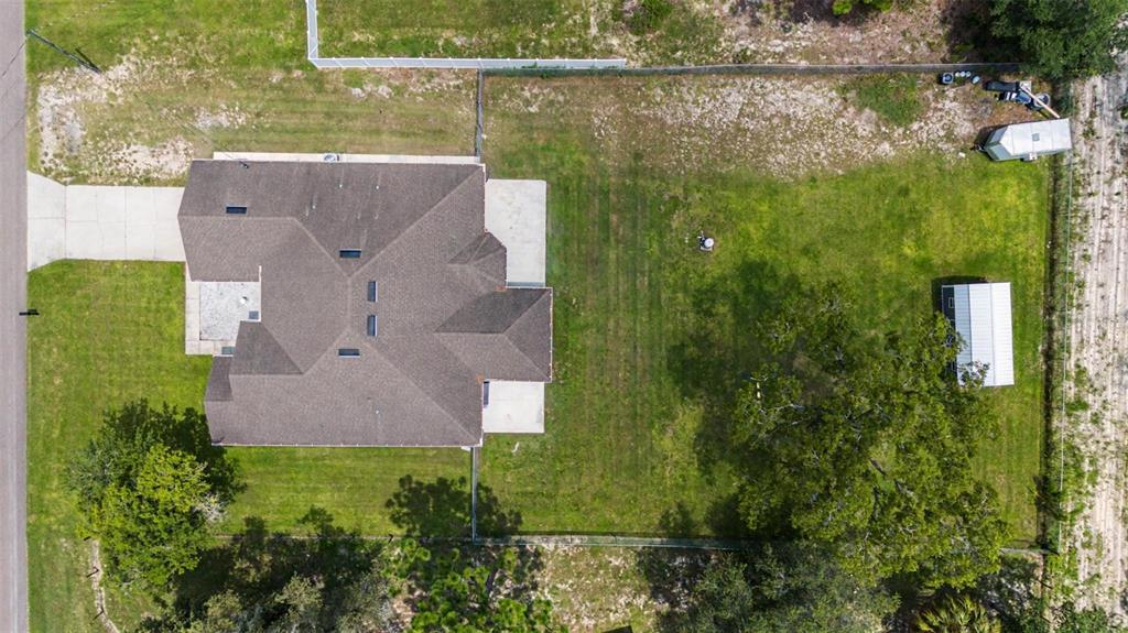 An aerial view shows a house with a large backyard, a shed, and fenced perimeter — 12258 HARRIS HAWK ROAD, WEEKI WACHEE, FL