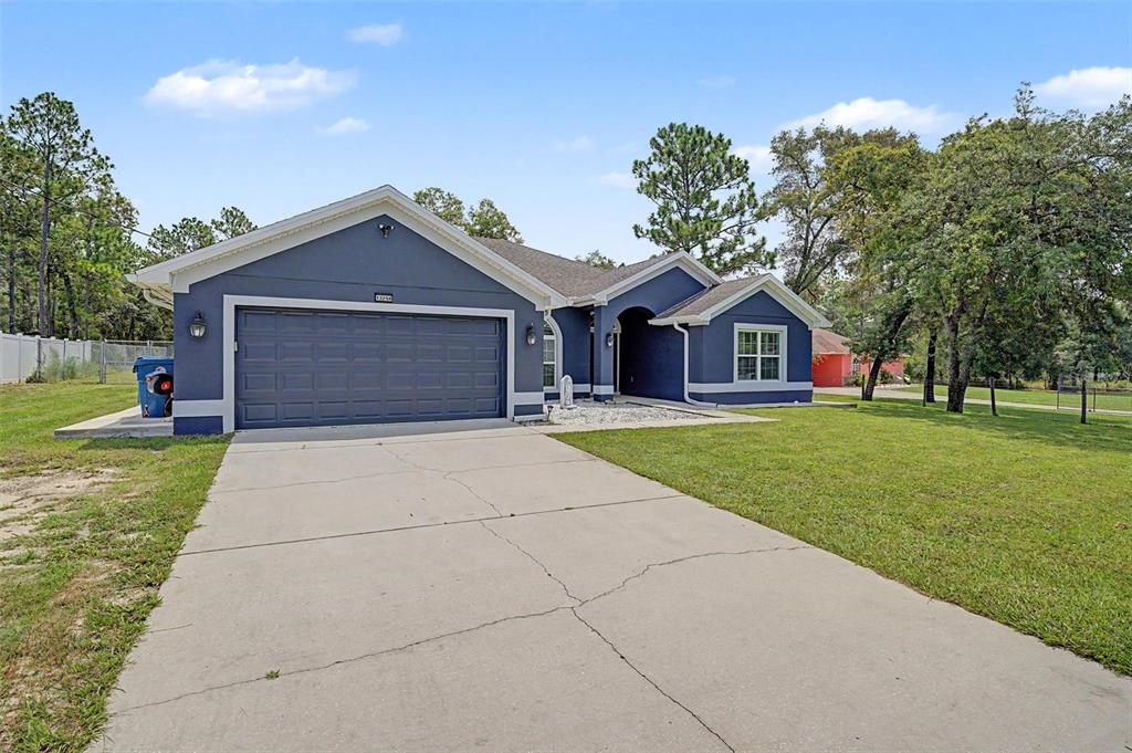 A blue single-story house with a two-car garage and a concrete driveway — 12258 HARRIS HAWK ROAD, WEEKI WACHEE, FL