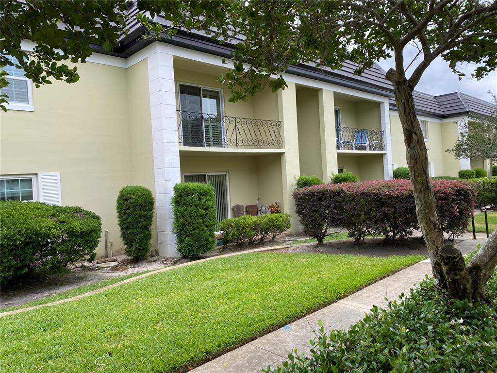 The exterior of a two-story apartment building features balconies, sliding glass doors, and manicured landscaping — 1500 GAY ROAD UNIT 17D, WINTER PARK, FL