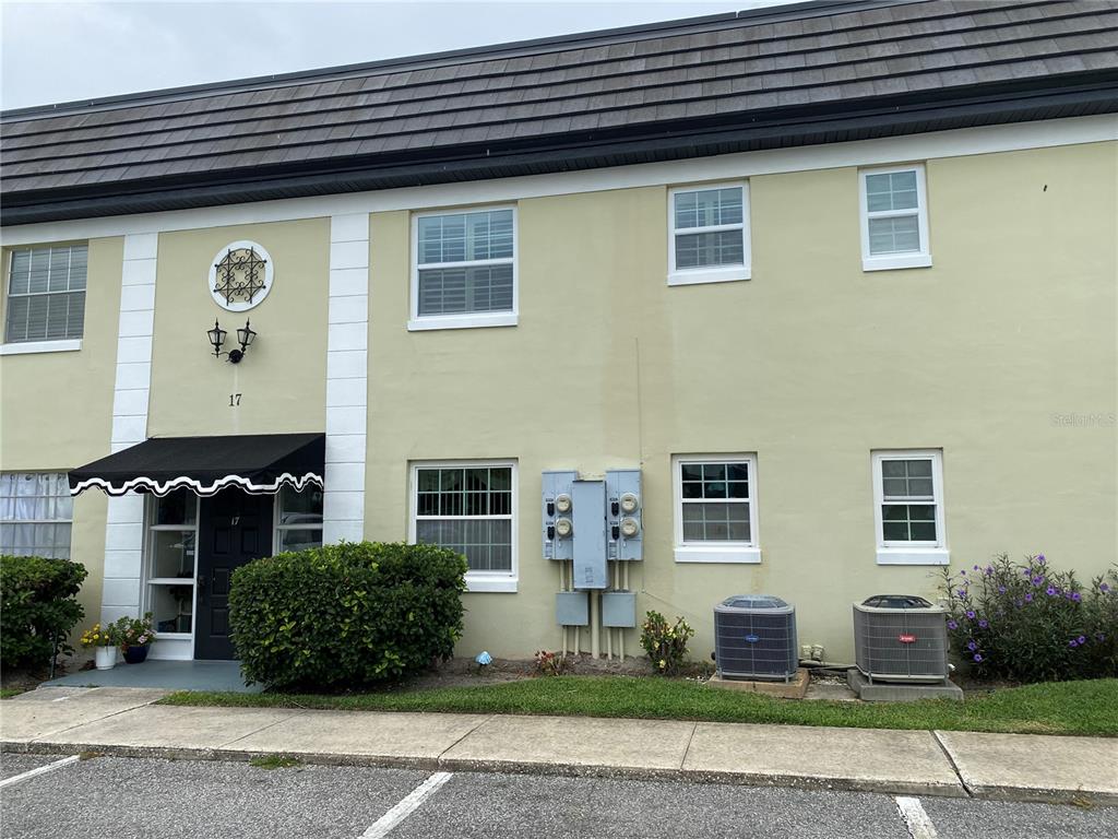 The exterior of a two-story apartment building features light yellow stucco walls and dark roofing — 1500 GAY ROAD UNIT 17D, WINTER PARK, FL