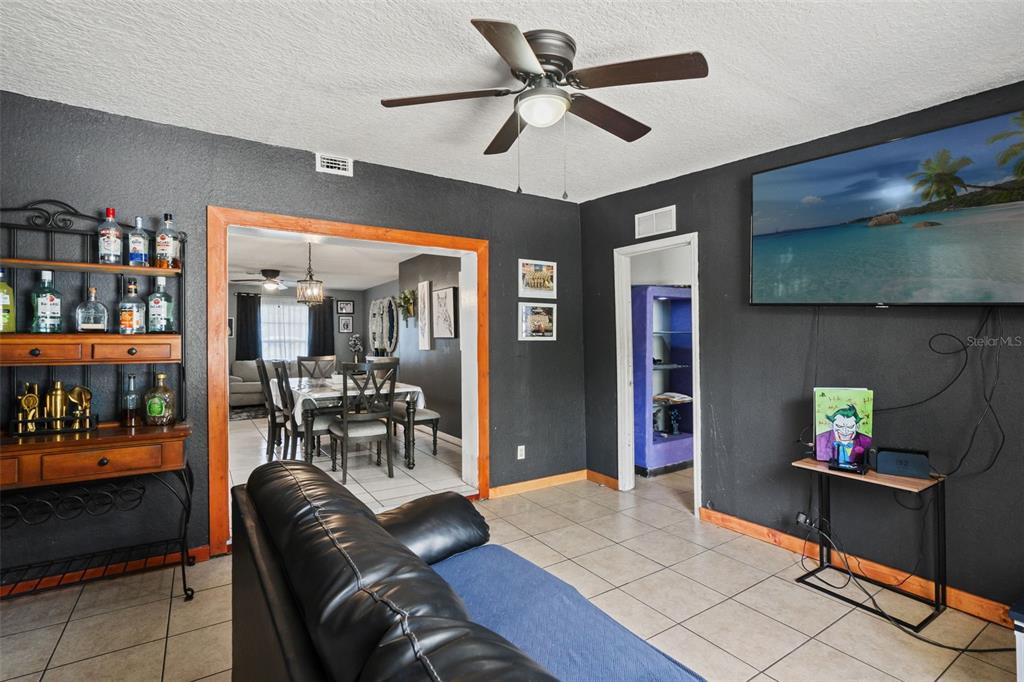 A living room with dark walls, tile flooring, a ceiling fan, and a dining area beyond — 12989 LINDEN DRIVE, SPRING HILL, FL