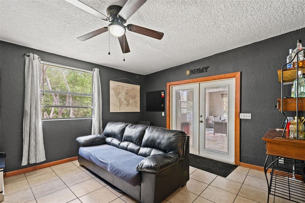 A living room features dark gray walls, a black leather sofa, and a ceiling fan — 12989 LINDEN DRIVE, SPRING HILL, FL