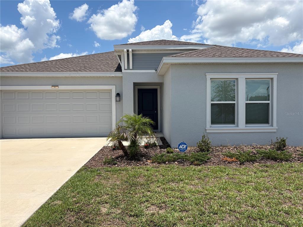 A single-story house with a gray stucco exterior, a two-car garage, and a front entrance — 309 SINGING SANDS CIRCLE, LAKE WALES, FL