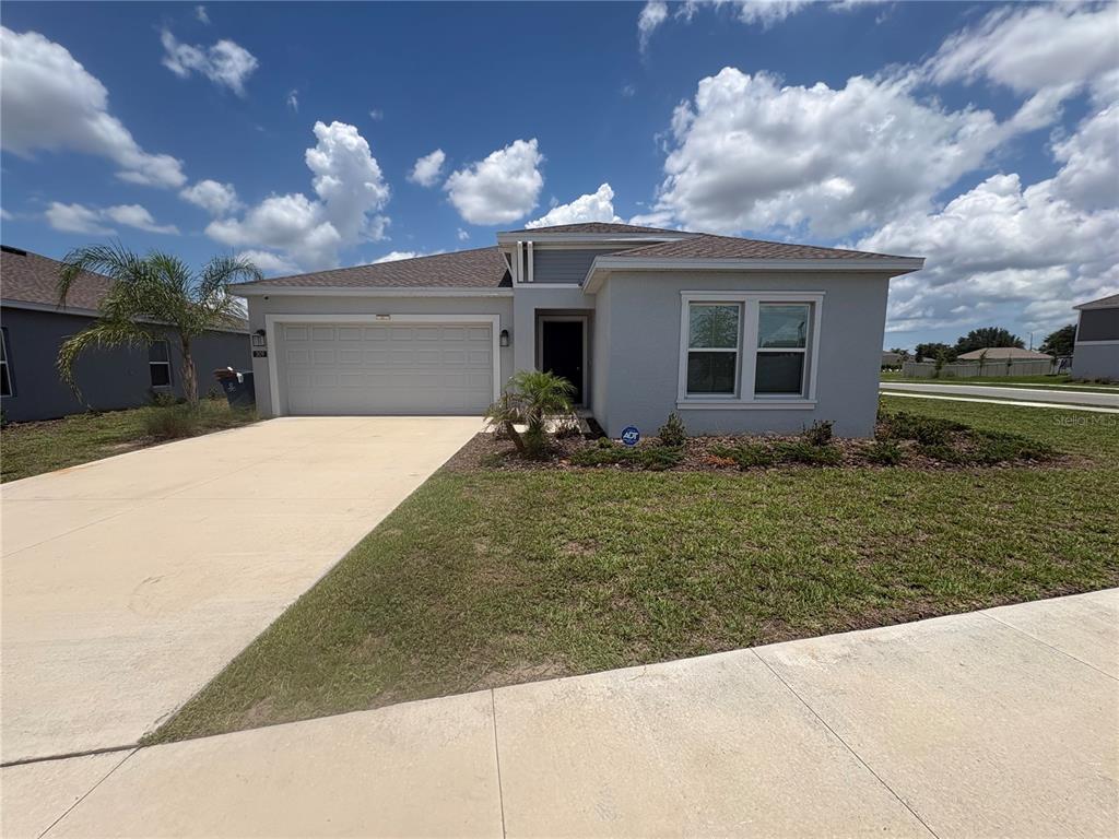 A single-story house with a gray stucco exterior, a two-car garage, and a concrete driveway — 309 SINGING SANDS CIRCLE, LAKE WALES, FL