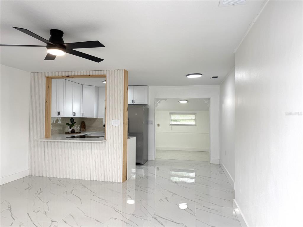 A kitchen with white cabinets and a pass-through window overlooks a tiled dining area — 4100 GARDEN STREET, TITUSVILLE, FL