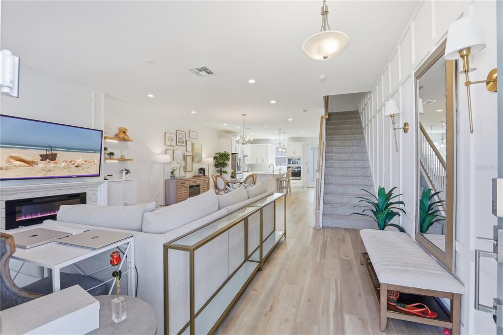 An open-concept living room and kitchen area features light wood flooring and a carpeted staircase — 13953 EASDALE ALLEY, WINTER GARDEN, FL