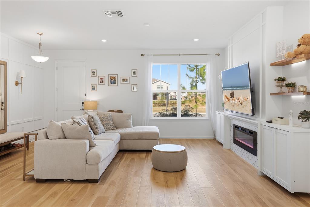 A living room features a sectional sofa, a fireplace with a television, and wood flooring — 13953 EASDALE ALLEY, WINTER GARDEN, FL