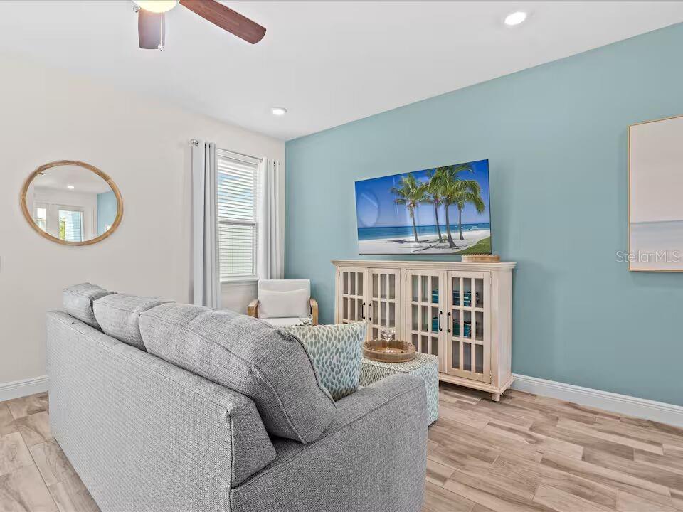 A living room features a gray sofa, a light blue accent wall, and a media console — 3193 CARIBBEAN SOUL DRIVE, KISSIMMEE, FL