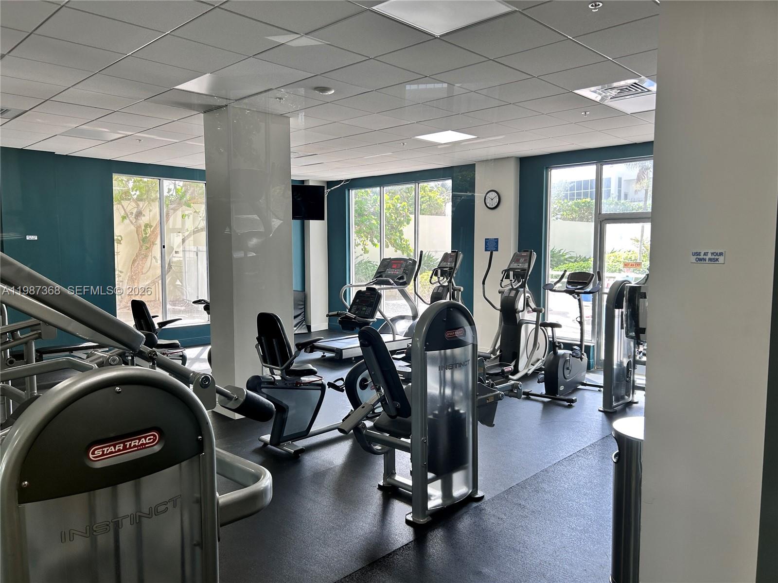A gym features various Star Trac exercise machines, large windows, and a drop ceiling — 4001 S Ocean Dr # 4G, Hollywood FL 33019, HOLLYWOOD, FL