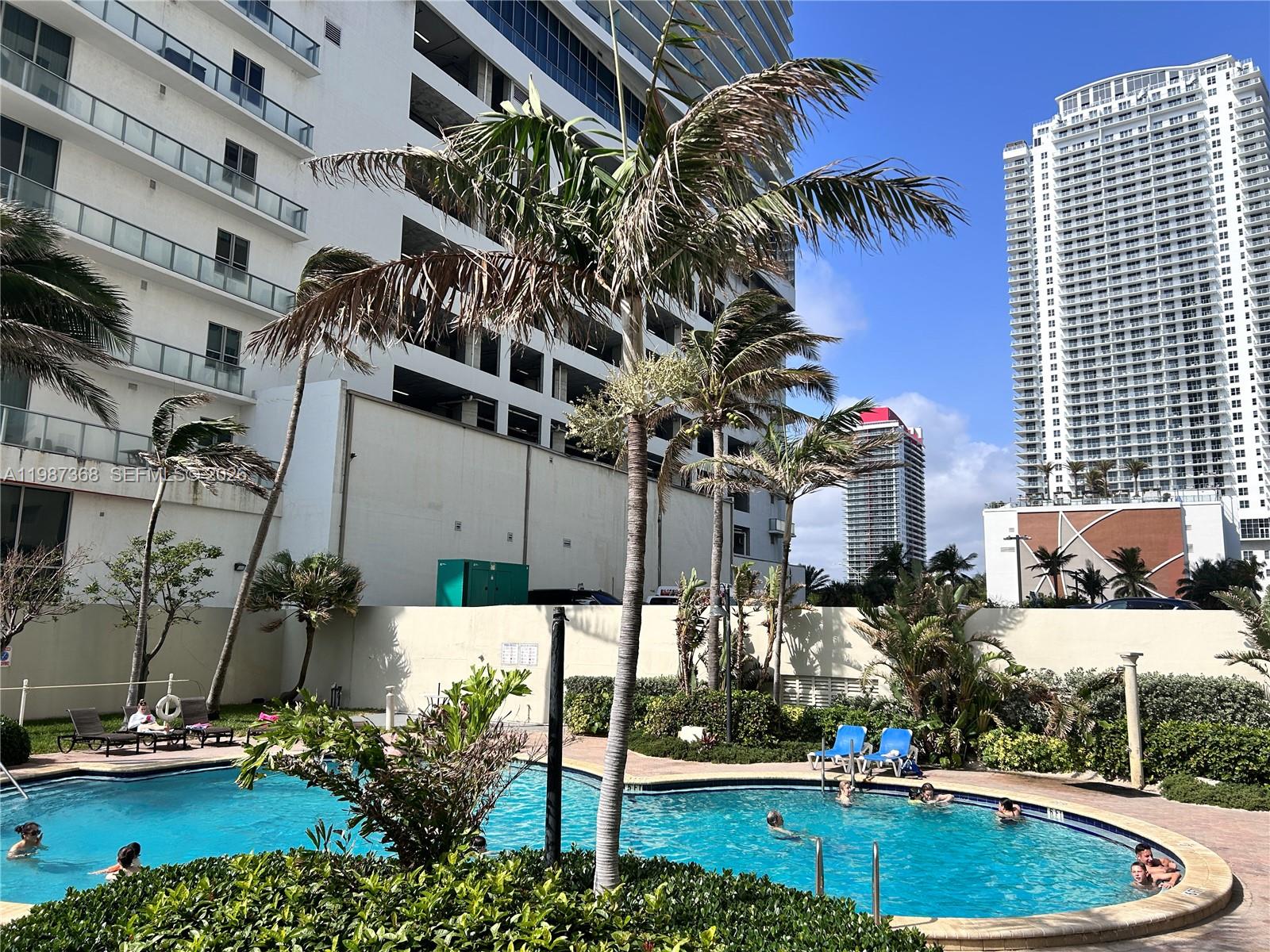 An outdoor swimming pool is surrounded by palm trees and high-rise apartment buildings — 4001 S Ocean Dr # 4G, Hollywood FL 33019, HOLLYWOOD, FL