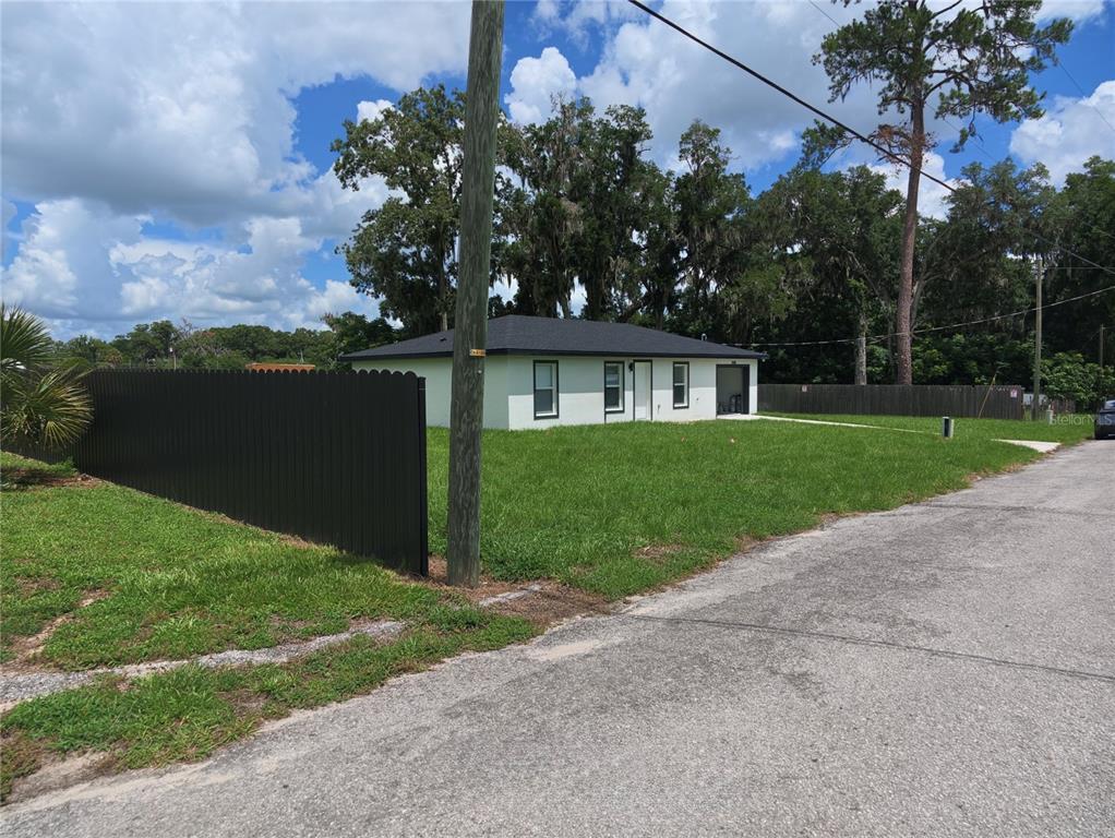 A single-story house with a black roof and white exterior sits on a grassy lot — 3400 SE 11TH AVENUE, OCALA, FL