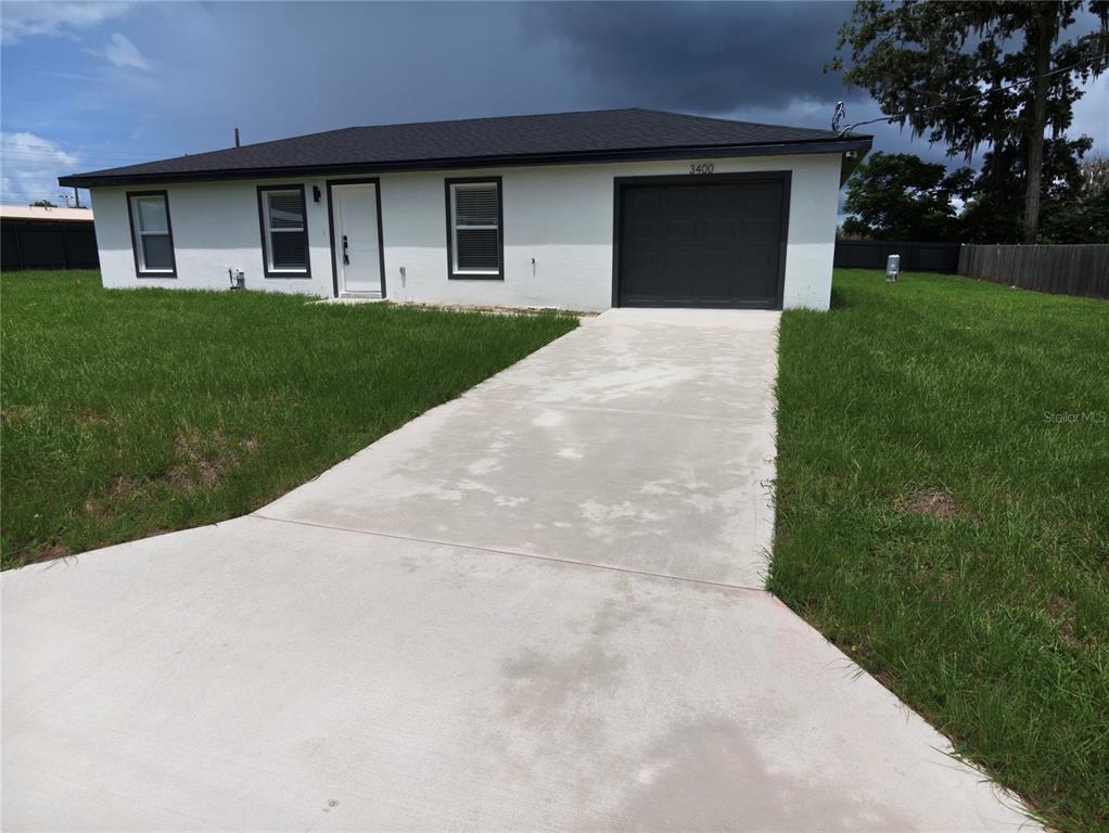 A single-story white house with a dark roof, garage, and concrete driveway sits on grass — 3400 SE 11TH AVENUE, OCALA, FL