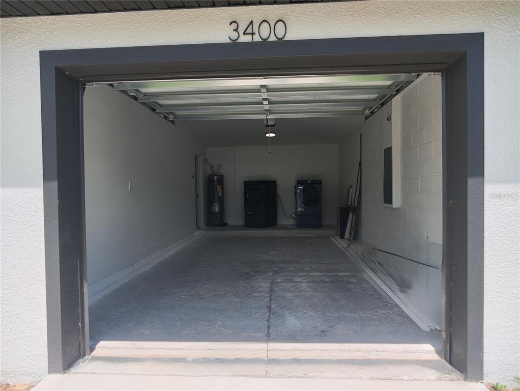 An open garage features a concrete floor, a water heater, and two laundry appliances — 3400 SE 11TH AVENUE, OCALA, FL