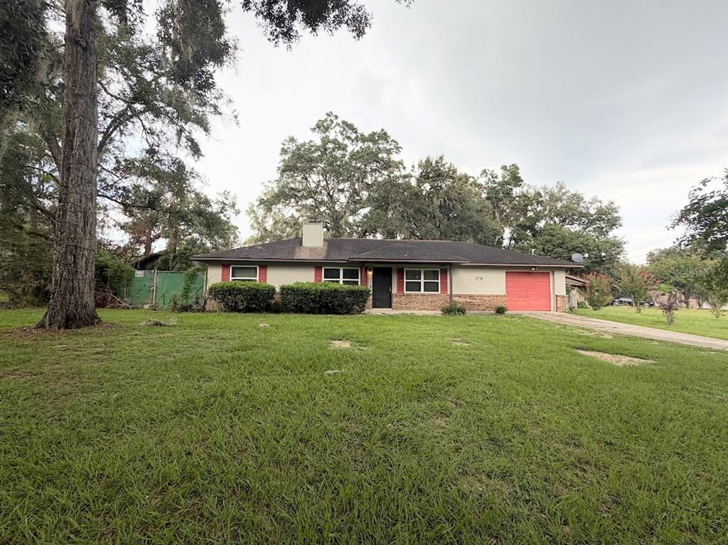 A single-story house with a red garage door, a chimney, and a large front lawn — 601 NE 27TH STREET, OCALA, FL
