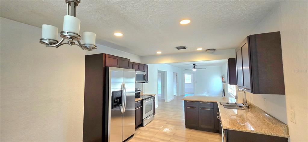 A kitchen features dark cabinets, stainless steel appliances, and light-colored wood-look flooring — 1313 CATHERINE STREET, ORLANDO, FL