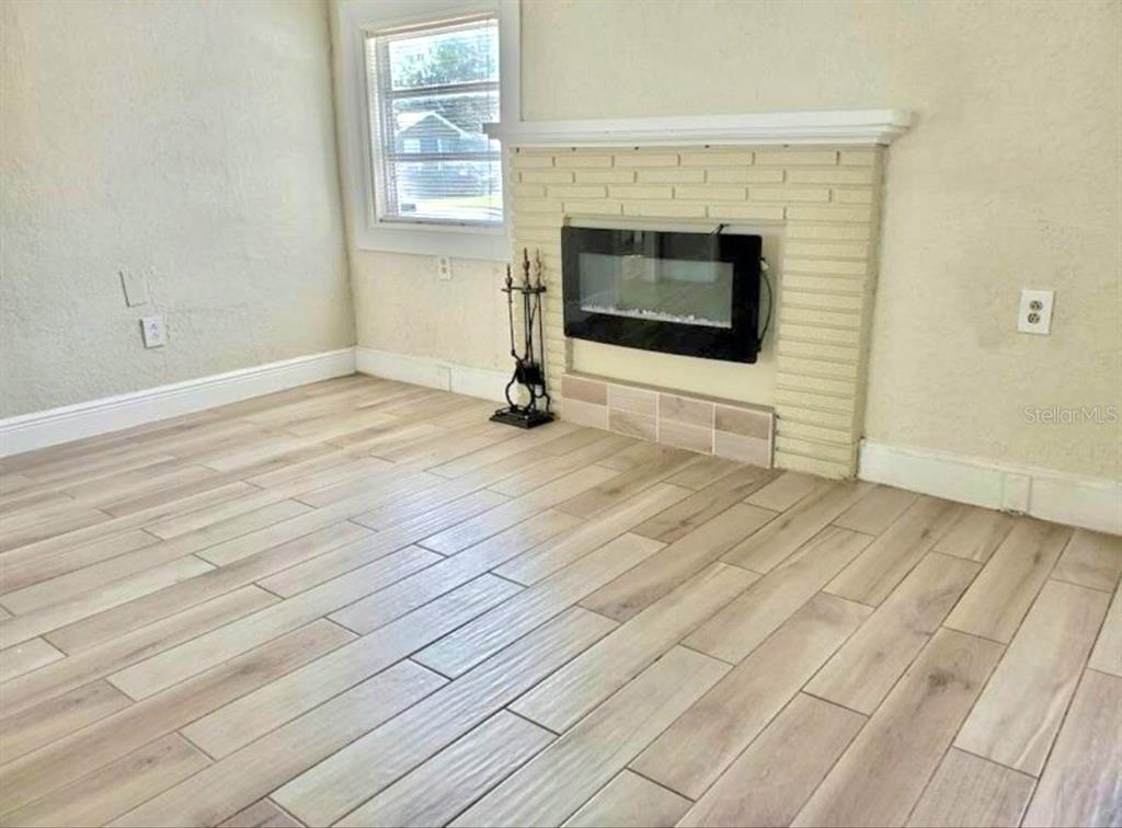 A living room with a fireplace, ceiling fan, and tile flooring leads into a kitchen — 1313 CATHERINE STREET, ORLANDO, FL
