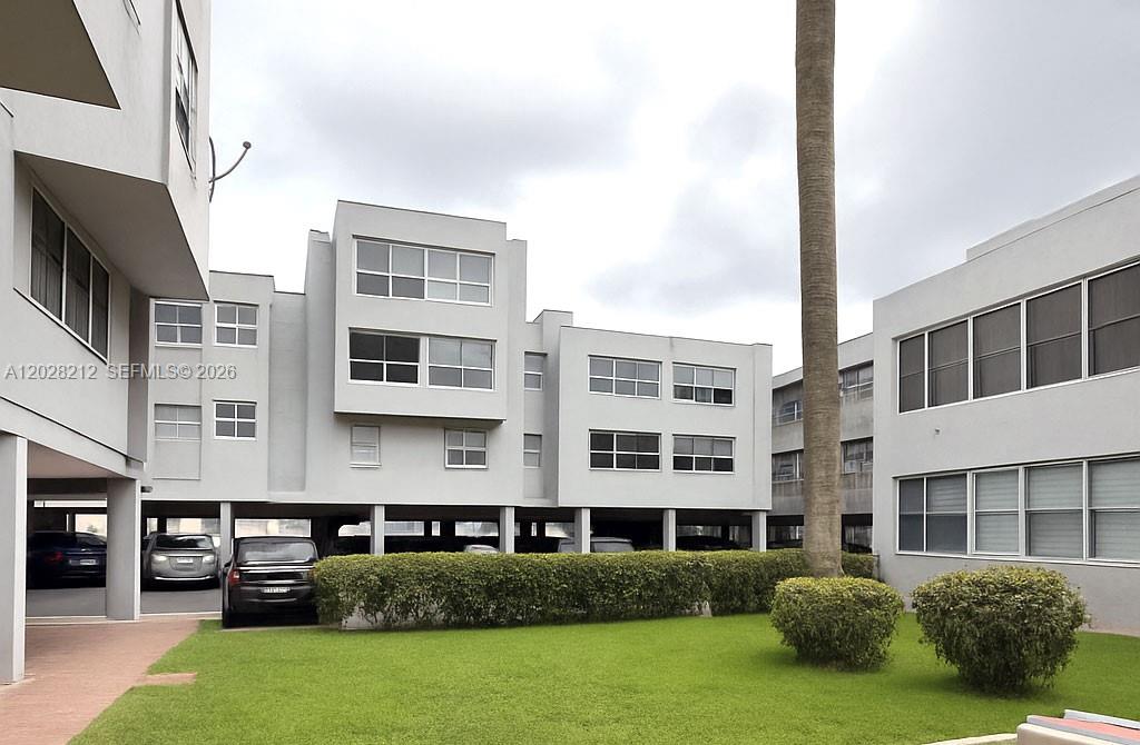 This exterior view shows a multi-story apartment building with covered parking and a lawn — 1555 W 44th Pl # 203, Hialeah FL 33012, HIALEAH, FL