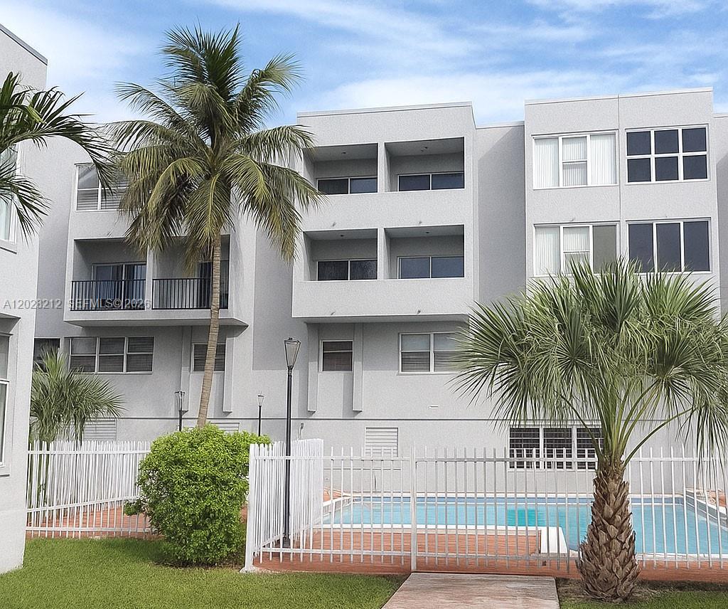 A multi-story apartment building with balconies overlooks a fenced swimming pool and palm trees — 1555 W 44th Pl # 203, Hialeah FL 33012, HIALEAH, FL